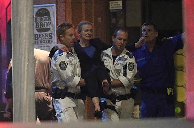 An injured hostage is carried to an ambulance after shots were fired during a cafe siege at Martin Place in the central business district of Sydney, Australia, Tuesday. (AP-Yonhap)