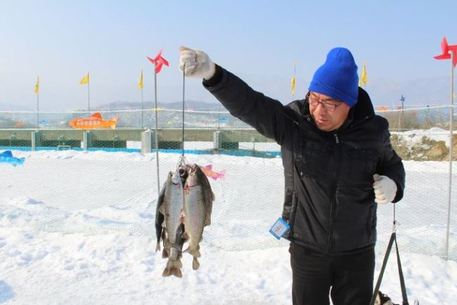 A visitor shows his catch during the Hwacheon Sancheoneo Ice Festival last year. (Hwacheon Sancheoneo Ice Festival)