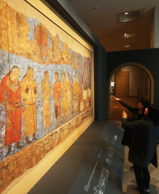 Students view a full-size replica of an Afrasiab mural painting at the National Museum of Korea in Seoul on Tuesday. It was drawn in the middle of the seventh century and discovered in Uzbekistan in 1965. The people in the painting are thought to be envoys of Goguryeo, an ancient Korean kingdom. (Yonhap)