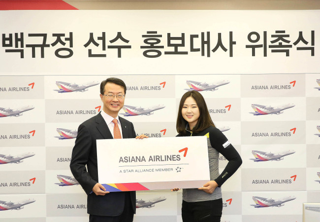 Asiana Airlines CEO Kim Soo-cheon (left) poses with pro-golfer Baek Kyu-jung after appointing her as the airline’s public relations ambassador in Seoul on Tuesday. (Asiana Airlines)