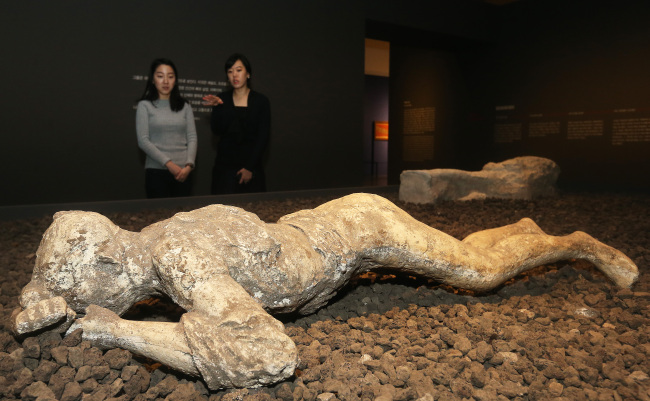 Visitors look at a plaster cast of a victim in the National Museum of Korea’s exhibition “Pompeii: Culture of The Ancient Roman City.” (Yonhap)