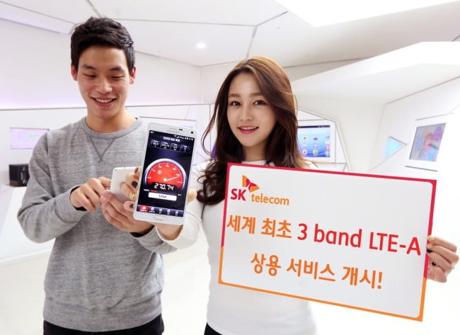 SK Telecom employees pose with a smartphone and a placard introducing the company’s tri-band LTE-A service. (SK Telecom)