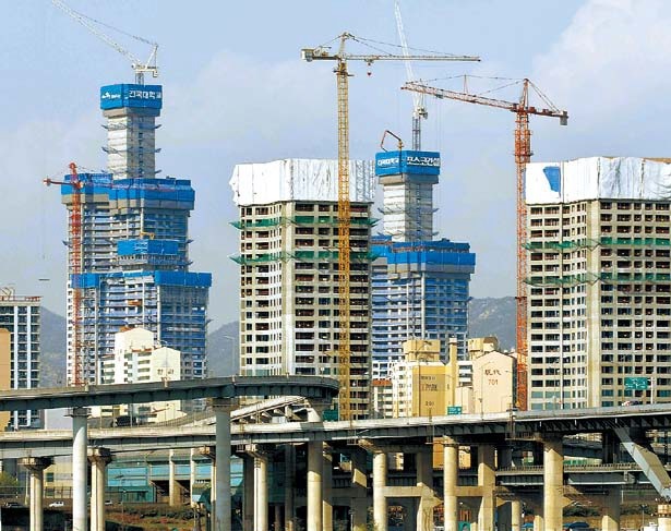 Apartment construction cranes move construction material at a POSCO Engineering and Construction construction site. (Bloomberg)