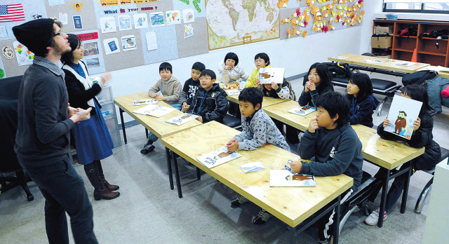 Elementary school students attend a class taught by a native English teacher. This photo is not directly related to the story.  (Korea Herald file photo)