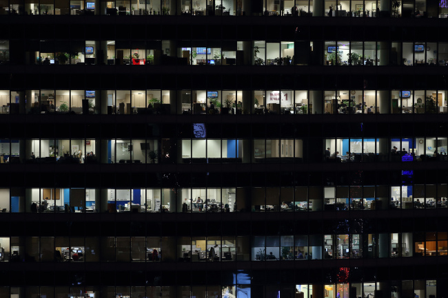 Office workers work in an illuminated office building at night in the Gangnam district in Seoul. (Bloomberg)