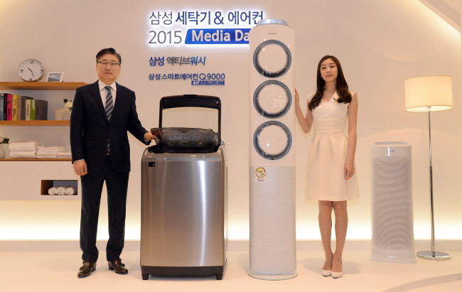 Samsung Electronics co-CEO Yoon Boo-keun (left) and figure skater Kim Yu-na, the brand’s commercial model, pose with amsung’s new washer and air conditioner at a media event at the company’s headquarters in Seoul on Tuesday. (Ahn Hoon/The Korea Herald)