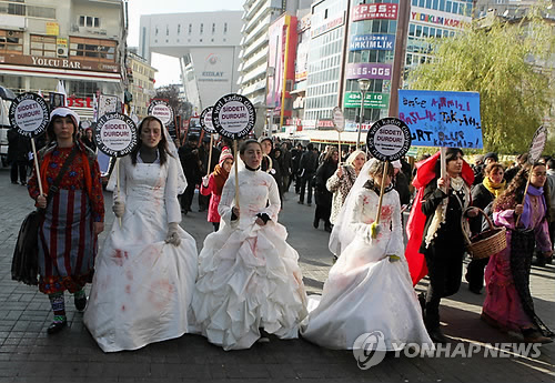 웨딩드레스를 입은 터키 여성 인권운동가들이 2011년 11월 '폭력종식'이라고 쓰인 플래카드를 들고 성폭행, 가정폭력 등에 반대하는 시위를 벌이고 있다. (AP=연합뉴스 자료사진)