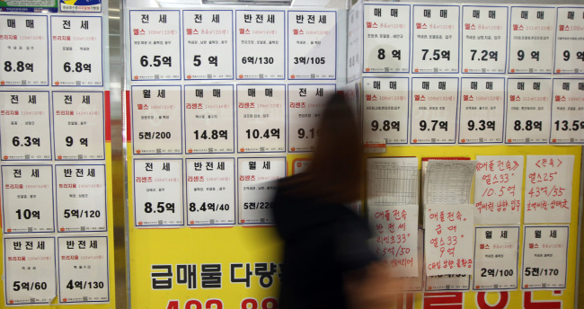 A woman walks past a real estate agency in Jamsil, Seoul. (Yonhap)