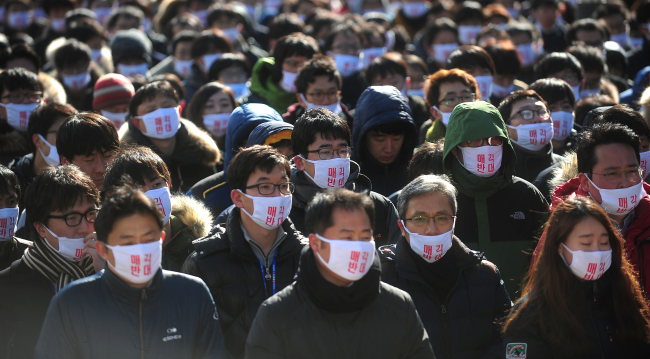 Samsung Techwin workers protest outside the group’s headquarters in southern Seoul in January. The masks (above) read “No sale.” (Yonhap)