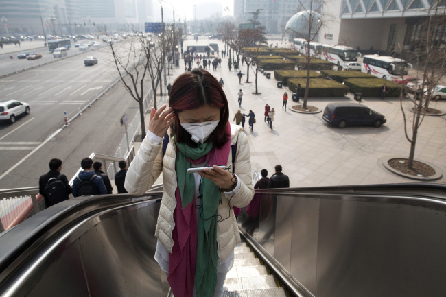 A woman wears a mask during a day of heavy pollution in Beijing on Saturday. (AP-Yonhap)