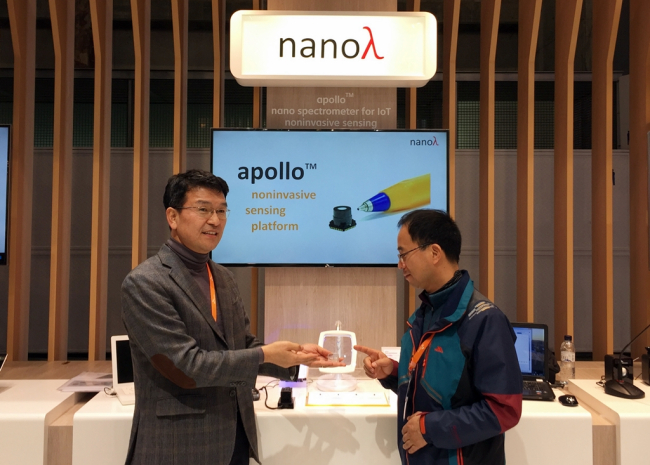 Choi Byung-il (left), the chief of the NanoLambda, introduces a spectrometer to visitors at the Mobile World Congress trade show held earlier this month. (SKT)