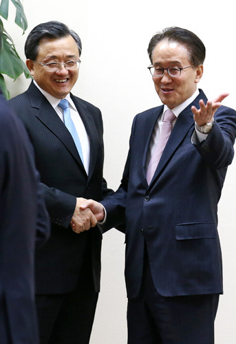 Deputy foreign ministers of China and South Korea join hands at a trilateral meeting in Seoul, September 2014. Liu Zhenmin (left) from China and Lee Kyung-soo from Korea. (Yonhap)