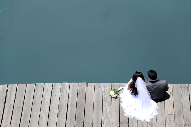 A bride and groom sit and watch the river. (123rf)