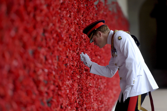 Britain’s Prince Harry places a poppy at the Roll of Honor during a visit to the Australian War Memorial in Canberra, Australia, Monday. Prince Harry, or Captain Harry Wales as he is known in the British Army, will end his military career with a monthlong assignment with the Australian Defense Force in barracks in Sydney, Perth and Darwin. (Related story on Page 18) (AP-Yonhap)