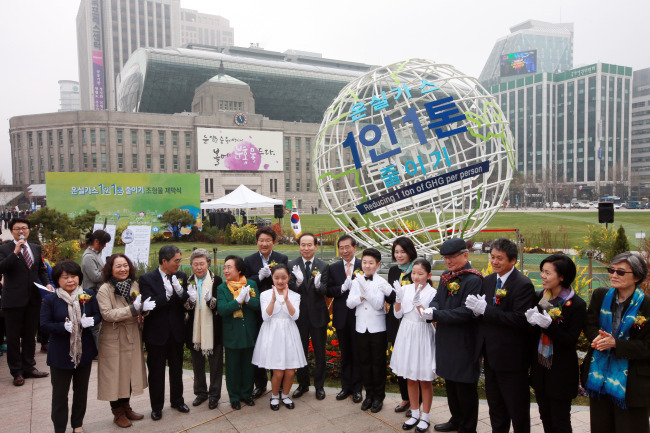 Seoul Mayor Park Won-soon (center) and other participants clap after unveiling the sculpture for the civic campaign “Reducing 1 Ton of Greenhouse Gas Per Person” at Seoul Plaza on Friday. (Yonhap)