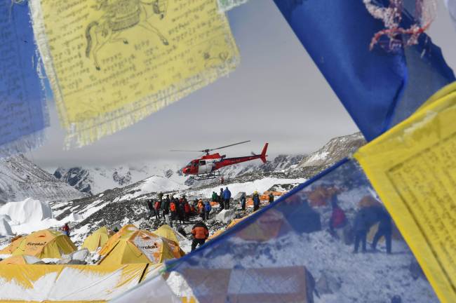 Prayer flags frame a rescue helicopter as it ferries the injured from Everest Base Camp on Sunday, a day after an avalanche triggered by an earthquake devastated the camp. (AFP-Yonhap)