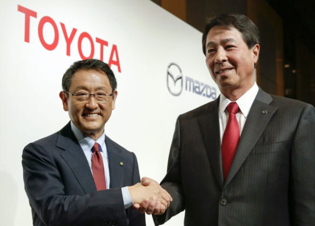 Toyota Motor CEO Akio Toyoda (left) and his Mazda Motor counterpart Masamichi Kogai pose at a press conference on May 13.