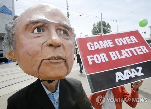 A protester wearing a mask depicting FIFA President Sepp Blatter stands in front of the building where the 65th FIFA congress takes place in Zurich, Switzerland, Friday. Yonhap