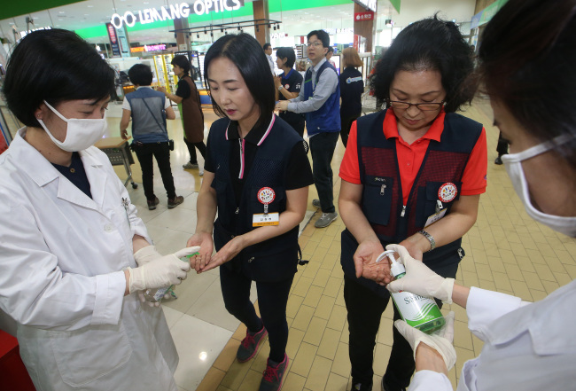 Employees of a supermarket disinfect their hands in Seoul on Tuesday. Yonhap