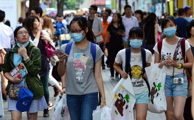 Tourists wearing masks walk along a street in Myeong-dong, downtown Seoul, Wednesday. (Yoon Byung-chan/The Korea Herald)