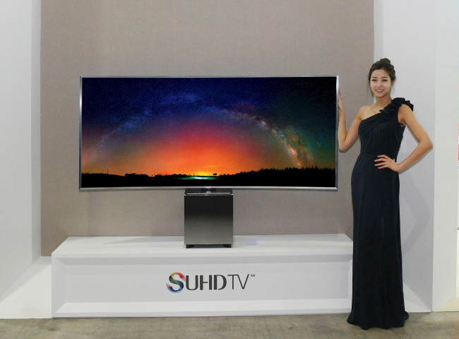 A model poses with Samsung Electronics’ newly released SUHD TV, 82S9W, which features an 82-inch curved display with a 21:9 aspect ratio, in Seoul on Monday. The electronics giant teamed up with world-renowned industrial designer Yves Behar for the design and packaging of the TV. (Samsung Electronics)