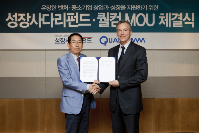 Qualcomm executive chairman Paul Jacobs (right) and Kim Young-deok, chairman of the advisory committee for the Growth Ladder Fund, shake hands after signing an MOU on supporting Korean start-ups in Samseong-dong, southern Seoul, Wednesday. (Qualcomm Korea)