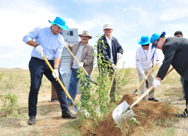 Oriental Brewery Co. CEO Kim Do-hun (far left) participates Tuesday in a commemorative planting in Erdene Sum, east of the Mongolian capital Ulan Bator. The Cass Forest of Life, a social contribution project to build a windbreak zone and to curb desertification, recently won the Land for Life Award from the United Nations Convention to Combat Desertification.OBC