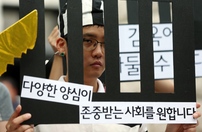 A member of a civic group supporting conscientious objectors holds a protest outside the Constitutional Court in Jongno-gu, Seoul, Thursday. (Yonhap)