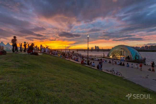 Music lovers sit along the riverside to attend a classical music concert as dusk gathers at Mulbit Square, Yeouido Hangang Park, near central Seoul. (Seoul Metropolitan Government)