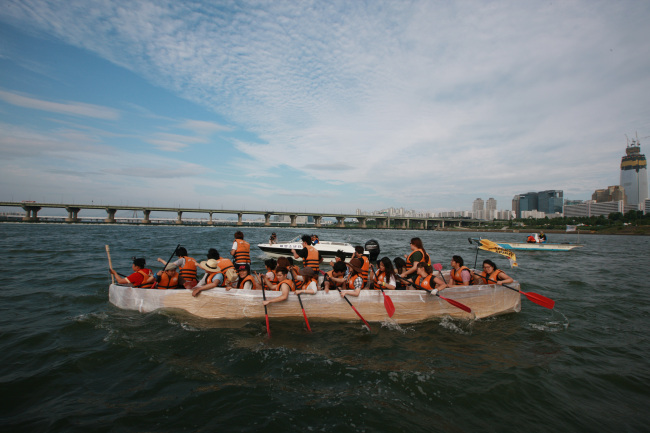A group of people on a boat built from recycled cardboard race across the Han River. (Seoul Metropolitan Government)