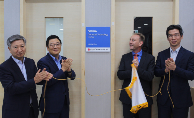 Kim Sun-tae (second from left), head of LG Uplus’ service and development division, and Adrew Cope (second from right), chief of Nokia Korea pose at a research and development center jointly established by the Korean mobile carrier and the network equipment manufacturer. LG Uplus