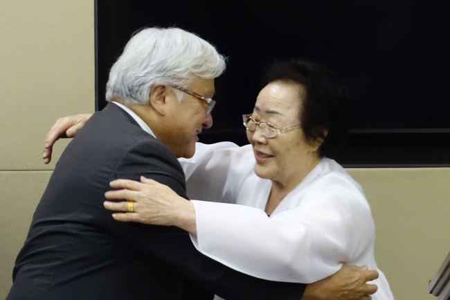U.S. lawmaker Mike Honda (left), a longtime supporter of the victims of Japan’s wartime sexual enslavement, and Lee Yong-su, one of the Korean victims, hug at a ceremony to mark the eighth anniversary of the passage of a U.S. congressional resolution on former sex slaves, in the Rayburn House Office Building in Washington on Tuesday. (Yonhap)