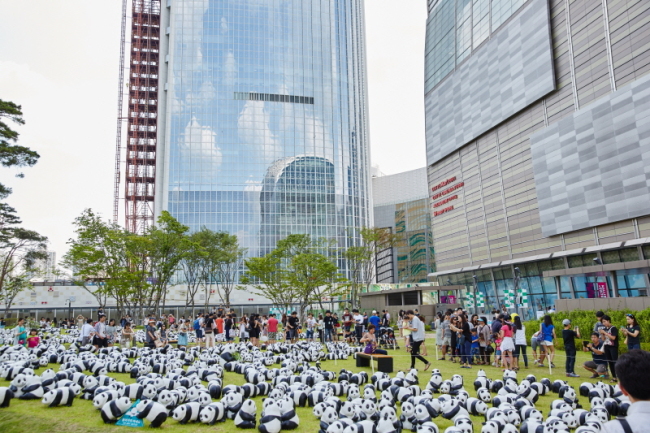 Visitors see 1,600 papier-mache pandas displayed in a garden at Lotte World Mall on Tuesday. AMHERST Photo by K-IMAGES