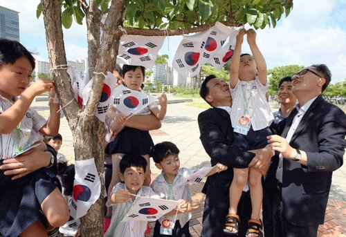 Children hoist national flag on to a tree to mark the approaching Liberation Day. (Yonhap)