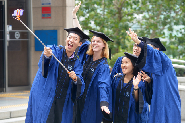 Graduates take selfies after their commencement ceremony at Hanyang University in Seoul in July. (Yonhap)