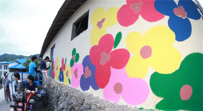 Students from Tongmyong University in Busan are drawing pictures on the wall in Bok-dong village, South Gyeongsang Province during a “Volunteer Activities for Rural Communities” event on July 21. (Yonhap)