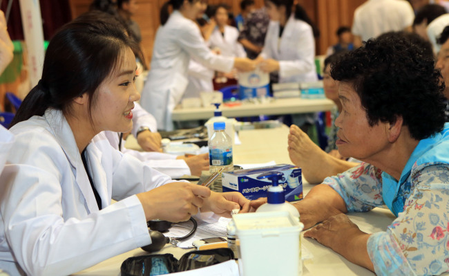 Students from Jeonbuk Science College‘s nursing department are checking blood pressure and glucose levels of the elderly at Chilbo Elementary in North Jeolla Province during a “Volunteer Activities for Rural Communities” event on July 23. (Yonhap)