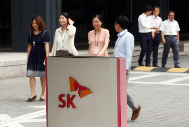 SK employees pass by the group headquarters in Seoul on Thursday, when its imprisoned chairman Chey Tae-won received a special pardon. Yonhap
