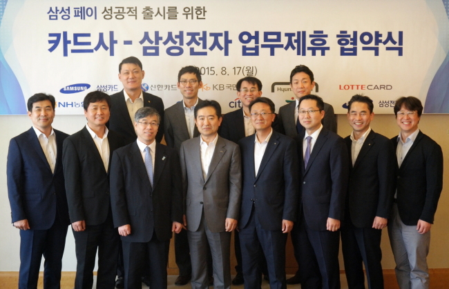 CARD ISSUERS GET SMART -- Samsung Electronics said Tuesday that it would collaborate with 10 credit card companies to nurture the Samsung Pay mobile payment service. Executives from the tech giant and the card firms, including KB Kookmin Card, Woori Card and Samsung Card, pose at a meeting to map out ways to work together on the mobile payment system in Seoul, Tuesday. (Samsung Electronics)