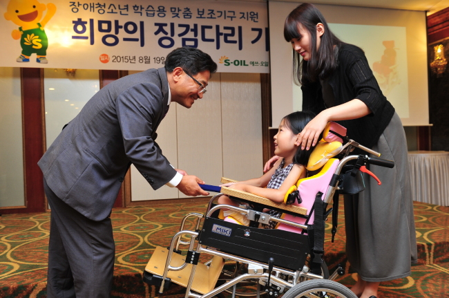 S-OIL AIDS DISABLED — S-Oil senior vice president Lee Chang-jae (left) delivers a customized study aid to a disabled student at the Gyeonggi Assistive Technology Research Assistance Center in Suwon, Gyeonggi Province, Wednesday. The firm handed over equipment worth 100 million won ($92,800) to 42 low-income disabled students on the same day, continuing its efforts to help disabled youths since 2010. (S-Oil)