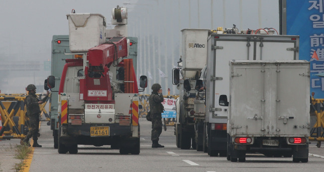 South Korean soldiers inspect vehicles at Tongil Bridge in Paju, Gyeonggi Province, before they cross the Imjin River to head for a joint industrial complex near the inter-Korean border Friday, a day after the rival Koreas traded fire across the Demilitarized Zone. Yonhap