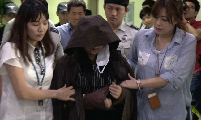 A woman accused of secretly filming women in the showers at a water park is escorted out of the police station in Yongin on Wednesday. (Yonhap)