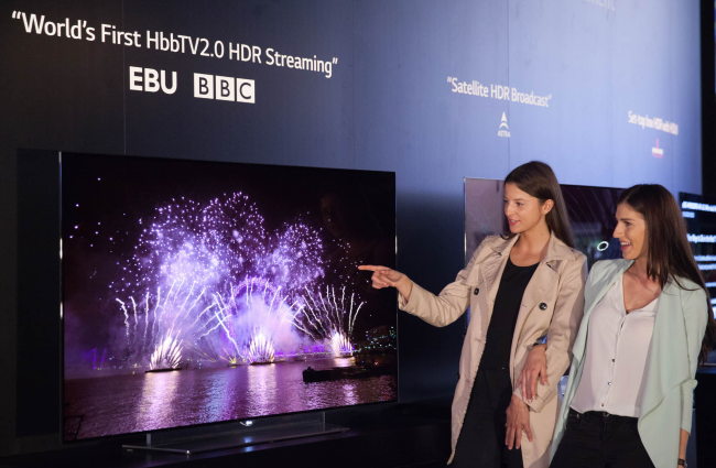 Models pose with LG Electronics’ OLED TV compatible with the HDR technology, which enhances the level of brightness and darkness. (LGE)