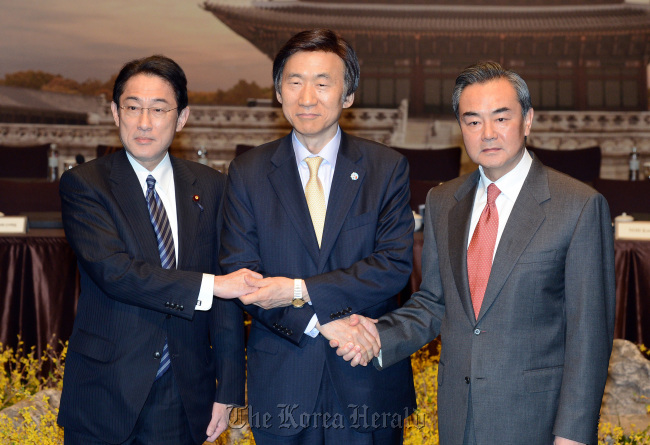 Seoul’s Foreign Minister Yun Byung-se (center) and his Chinese and Japanese counterparts, Wang Yi (right) and Fumio Kishida, pose after their meeting on March 22 in Seoul. (Yonhap)