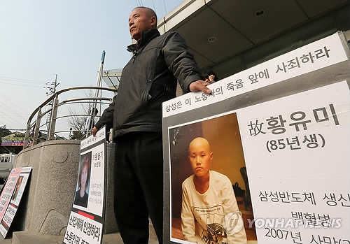 Hwang Sang-ki, the father of Hwang Yu-mi--a former Samsung Electronics worker who died from lukemia in 2007--holds banners at Samsung`s chip factory in Giheung, Gyeonggi Province, urging Samsung to take reponsibility for the death of her dauther. (Yonhap)