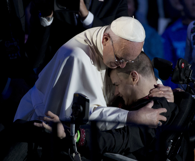 Pope Francis embraces a young man in a wheelchair during the World Meeting of Families in the Benjamin Franklin Parkway Saturday, Sept. 26, 2015, in Philadelphia. (AP Photo)