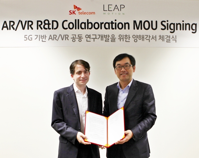 EXPLORATION OF VIRTUAL REALITY TECH -- Choi Jin-sung (right), chief technology officer of SKT, and Leap Motion CEO Michael Buckwald pose after signing a partnership agreement in Seoul on Thursday. SK has sought a global partner to develop virtual reality multimedia services. (SKT)