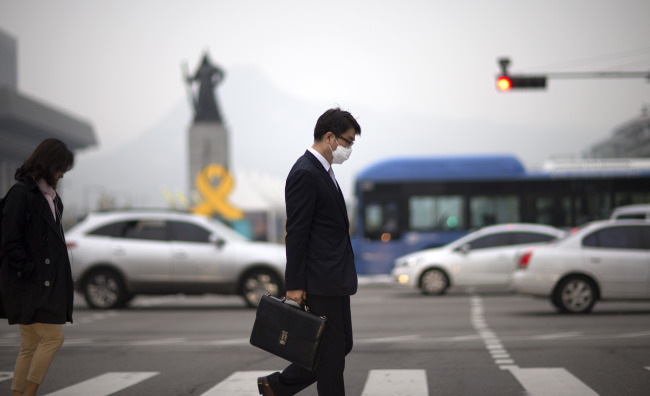 A pedestrian walks wearing a mask in Gwanghwamun in central Seoul on Tuesday. Yonhap