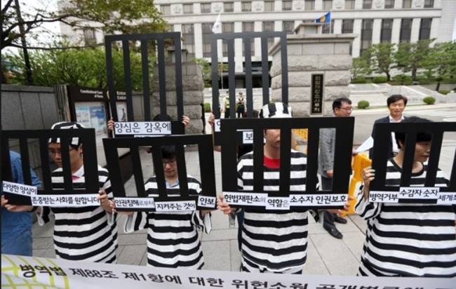 Civic activits stage a performance supporting conscientious objectors outside the Constitutional Court in Seoul in July, during a public hearing on whether to allow people to refuse mandatory military service based on their religious or personal beliefs. (Yonhap)