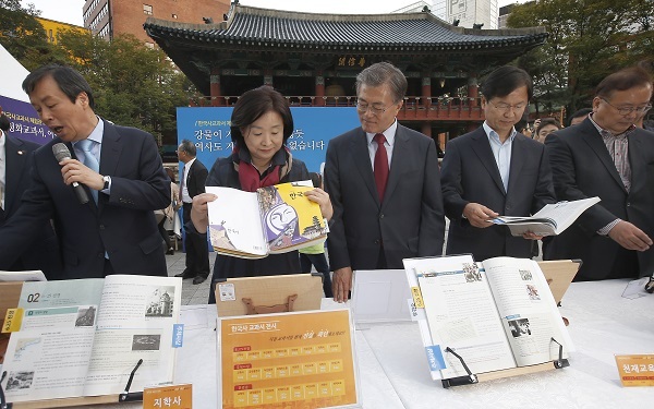 Opposition lawmakers including New Politics Alliance for Democracy chairman Rep. Moon Jae-in (center) browse through Korean history textbooks displayed at an exhibition opened at Bosingak park in downtown Seoul as part of the rallies to oppose state-authored textbook on Sunday. Yonhap